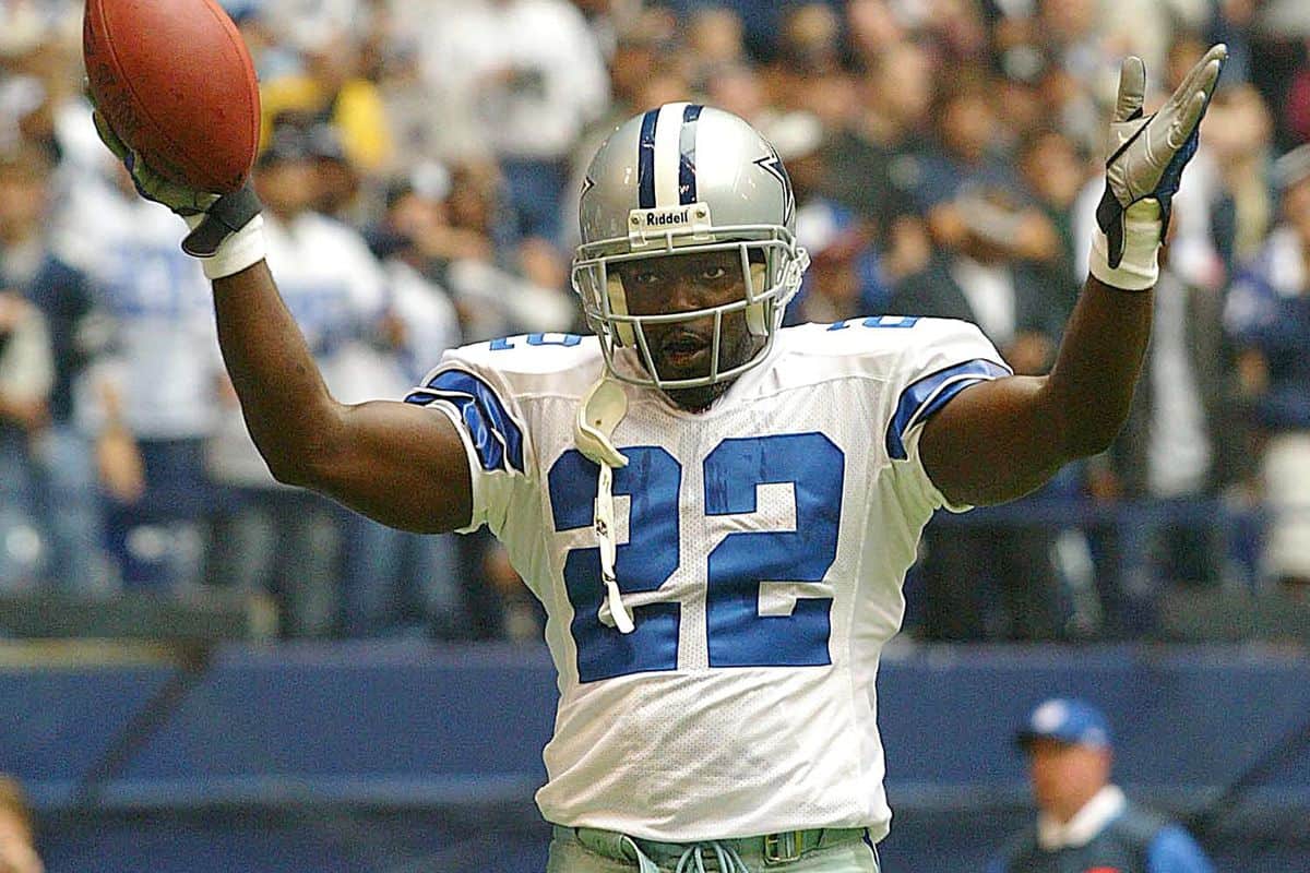 Player in a Dallas Cowboys football jersey celebrating with arms raised during a game.