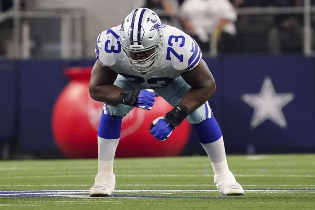 Aggressive Dallas Cowboys linebacker in offensive stance on football field, wearing team uniform and helmet during game.