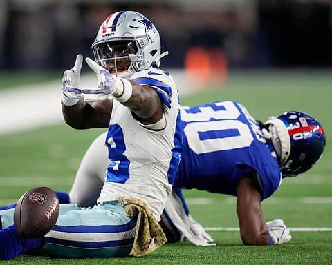 Solid football player making a play on the field during a game; Dallas Cowboys player in action against an opposing team.