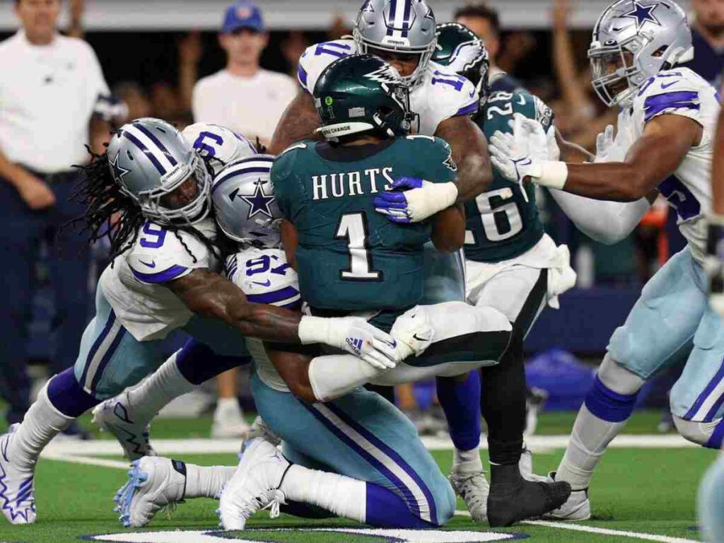 Dallas Cowboys defenders tackle a Philadelphia Eagles player during an NFL game. Inside The Star focuses on Cowboys' game analysis, player updates, and team insights for dedicated fans.