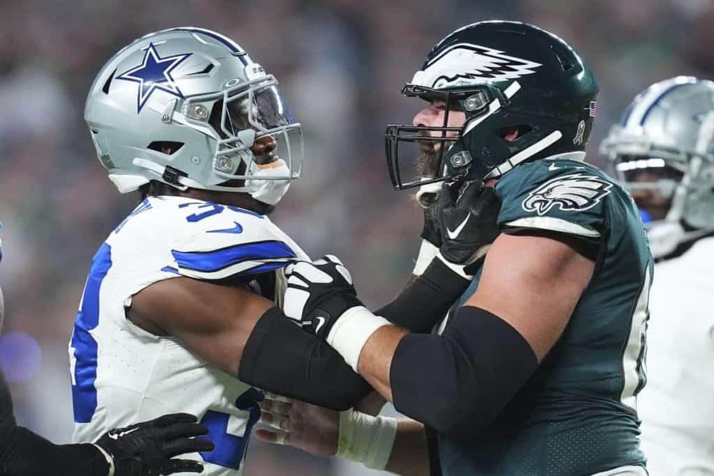 Dallas Cowboys player and Philadelphia Eagles player face off on the football field, showcasing intense rivalry and sportsmanship in an NFL game.