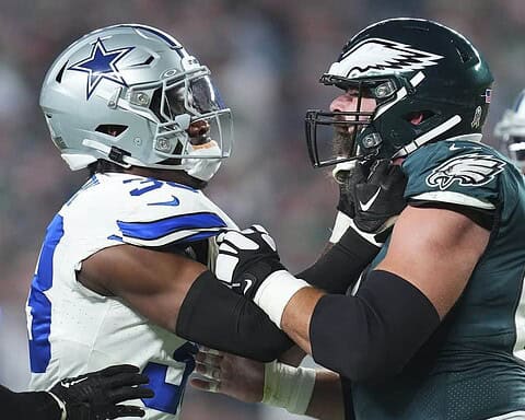 Dallas Cowboys player and Philadelphia Eagles player face off on the football field, showcasing intense rivalry and sportsmanship in an NFL game.