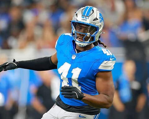 Detroit Lions football player in action during a game, wearing a blue jersey and helmet, focused on the game.