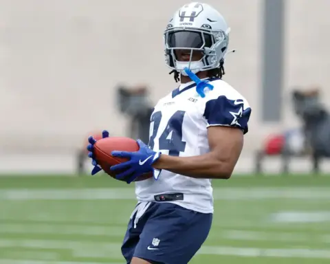 High school football player in Dallas Cowboys uniform holding football during practice.