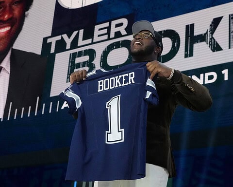 Young man holding Dallas Cowboys football jersey with "Booker" and number 1 at a draft or signing event, showcasing NFL team talent and player signing highlights.