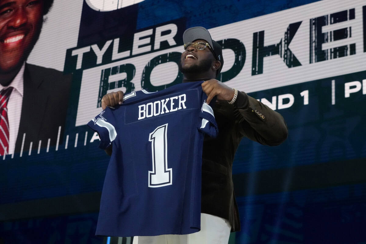 Young man holding Dallas Cowboys football jersey with "Booker" and number 1 at a draft or signing event, showcasing NFL team talent and player signing highlights.