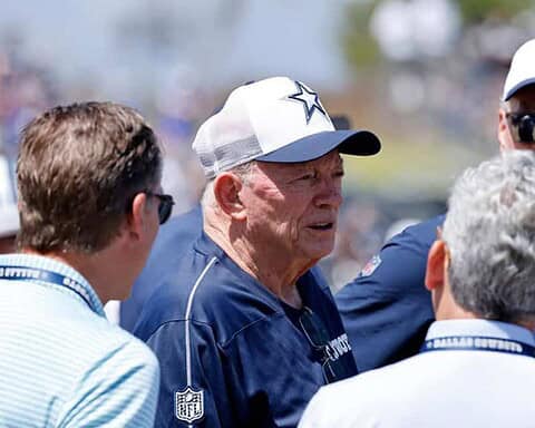 Senior Dallas Cowboys coach talking with team members, NFL game strategy discussion, inside the star, American football fans, Texas stadium, sports team management, Inside The Star image.