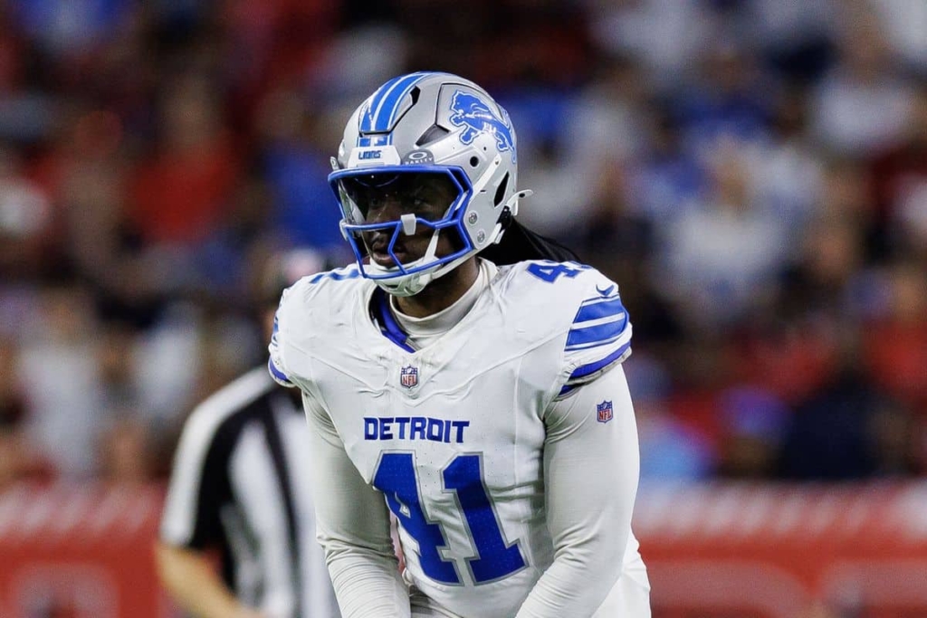 High school football player in Detroit Lions uniform with helmet on during game, representing the Detroit Lions NFL team.