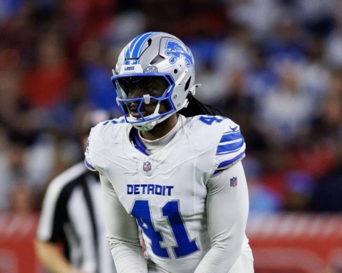 High school football player in Detroit Lions uniform with helmet on during game, representing the Detroit Lions NFL team.