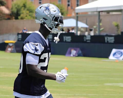 Dallas Cowboys football player wearing helmet and jersey during practice at training camp.
