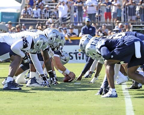 Dallas Cowboys offensive line prepares for the snap during an NFL game at AT&T Stadium, showcasing team strategy and athleticism.