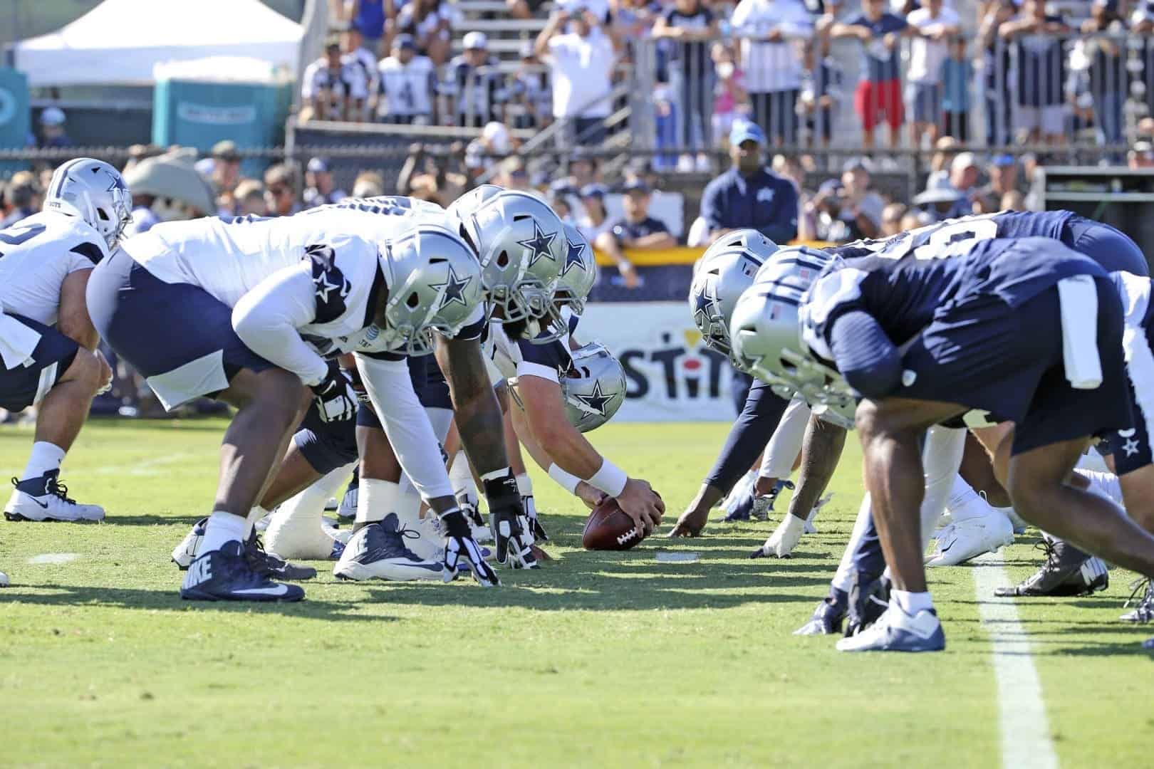 Dallas Cowboys offensive line prepares for the snap during an NFL game at AT&T Stadium, showcasing team strategy and athleticism.