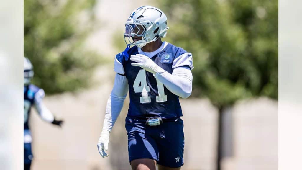 Aggressive Dallas Cowboys football player during practice on sunny day in full gear.