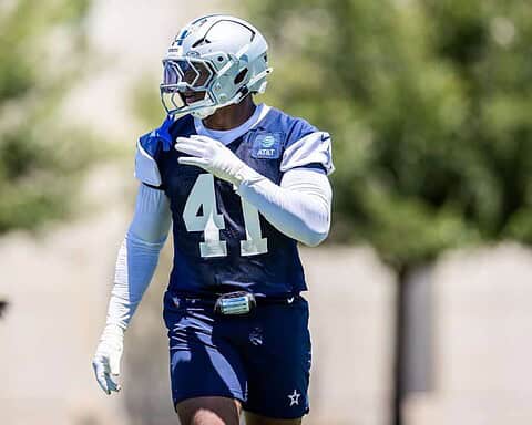 Aggressive Dallas Cowboys football player during practice on sunny day in full gear.