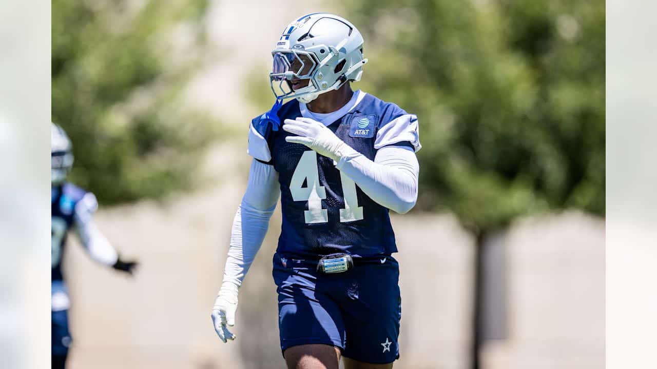 Aggressive Dallas Cowboys football player during practice on sunny day in full gear.