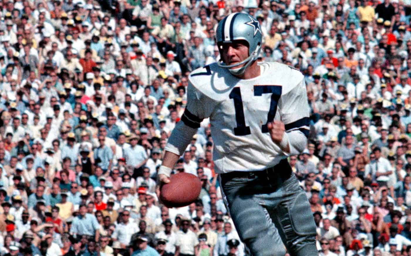Running Dallas Cowboys quarterback with helmet wearing jersey number 17 holding football on field filled with cheering crowd.