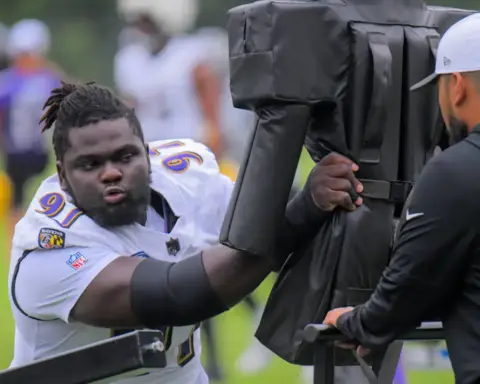 - Young football player practicing training drills with tackling dummy at practice field.
