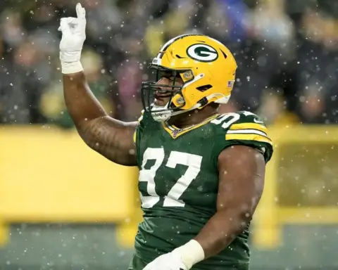 Green Bay Packers football player wearing yellow helmet and dark green jersey with the number 32, celebrating on the field during a game in the rain.