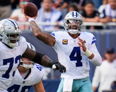 Quarterback Dak Prescott throwing a football during a Dallas Cowboys game, with teammates and fans in the background. Action-packed NFL scene showcasing team leadership and football skills.