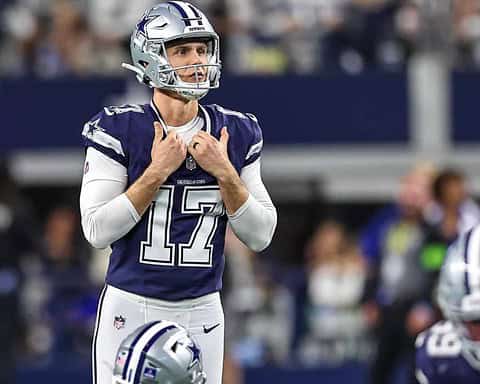 Quarterback Dak Prescott wearing Dallas Cowboys uniform during NFL game, standing on the field with helmet on, focused on the game, showing team spirit and leadership.