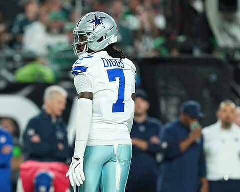 DaqoardDallas Cowboys football player wearing helmet and uniform on sideline during game at AT&T Stadium.