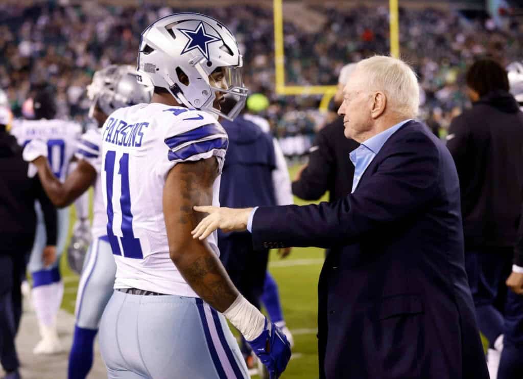 Dallas Cowboys player talking with coach on the sideline during an NFL game, showcasing team strategy and leadership.