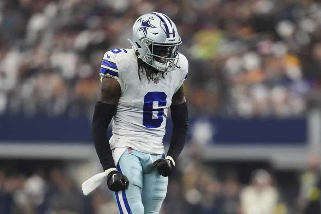 Dallas Cowboys football player celebrating during a game, wearing team uniform and helmet, on the field with blurred crowd background.