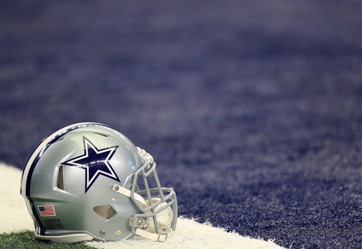 Dallas Cowboys football helmet on the field, close-up, showcasing team logo and American flag detail, with a background of the football field turf. Perfect for NFL and Dallas Cowboys fan content.