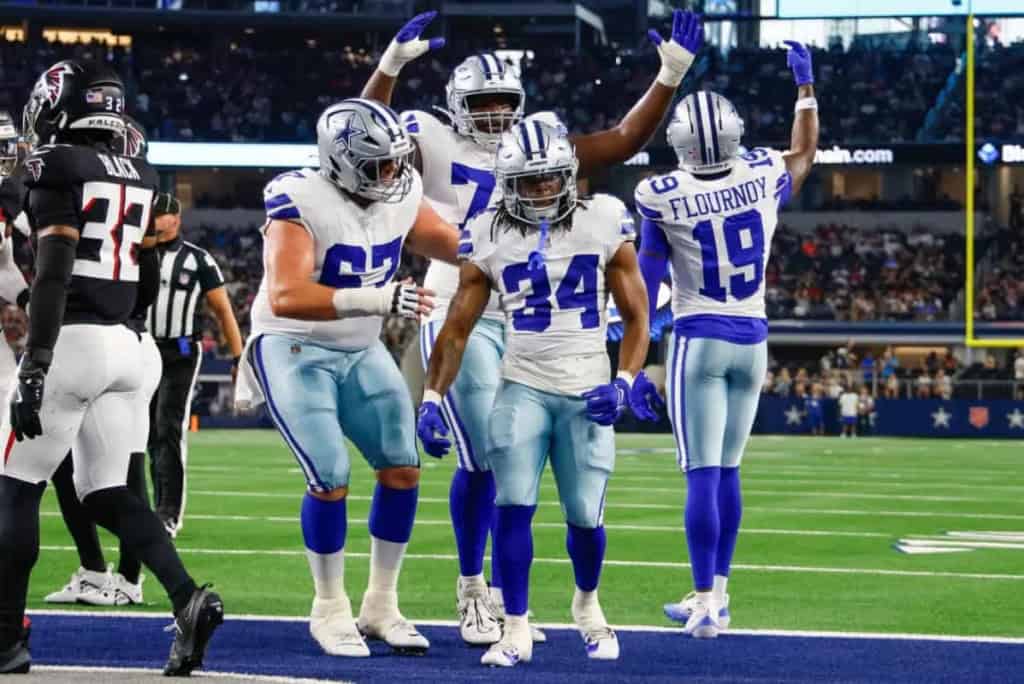 Dallas Cowboys football players celebrating on the field during a game at AT&T Stadium.