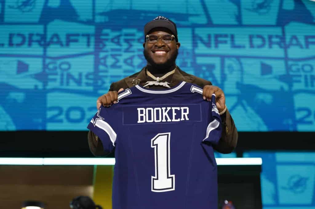 Dallas Cowboys player holding up his new jersey at the NFL Draft, showcasing team pride and excitement for the upcoming football season.