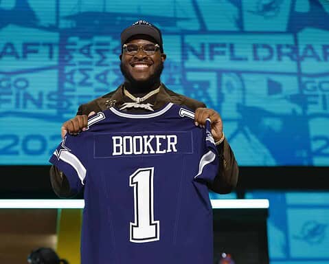 Dallas Cowboys player holding up his new jersey at the NFL Draft, showcasing team pride and excitement for the upcoming football season.