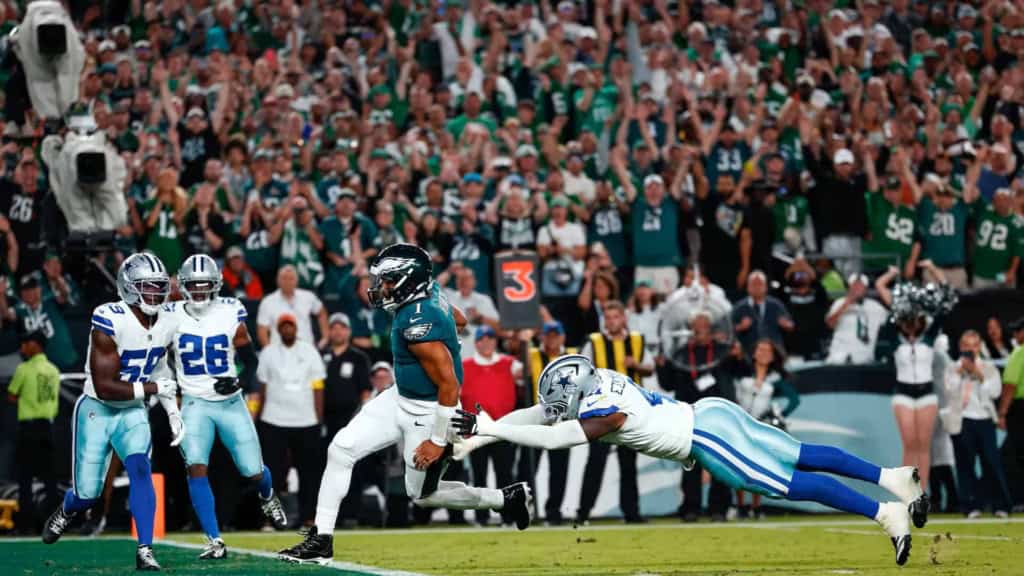 Spectacular football game action with a player from the Philadelphia Eagles evading a tackle from a Dallas Cowboys defender on the field during a high-stakes NFL game.