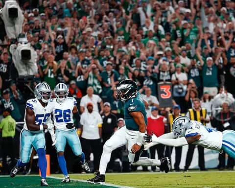 Spectacular football game action with a player from the Philadelphia Eagles evading a tackle from a Dallas Cowboys defender on the field during a high-stakes NFL game.