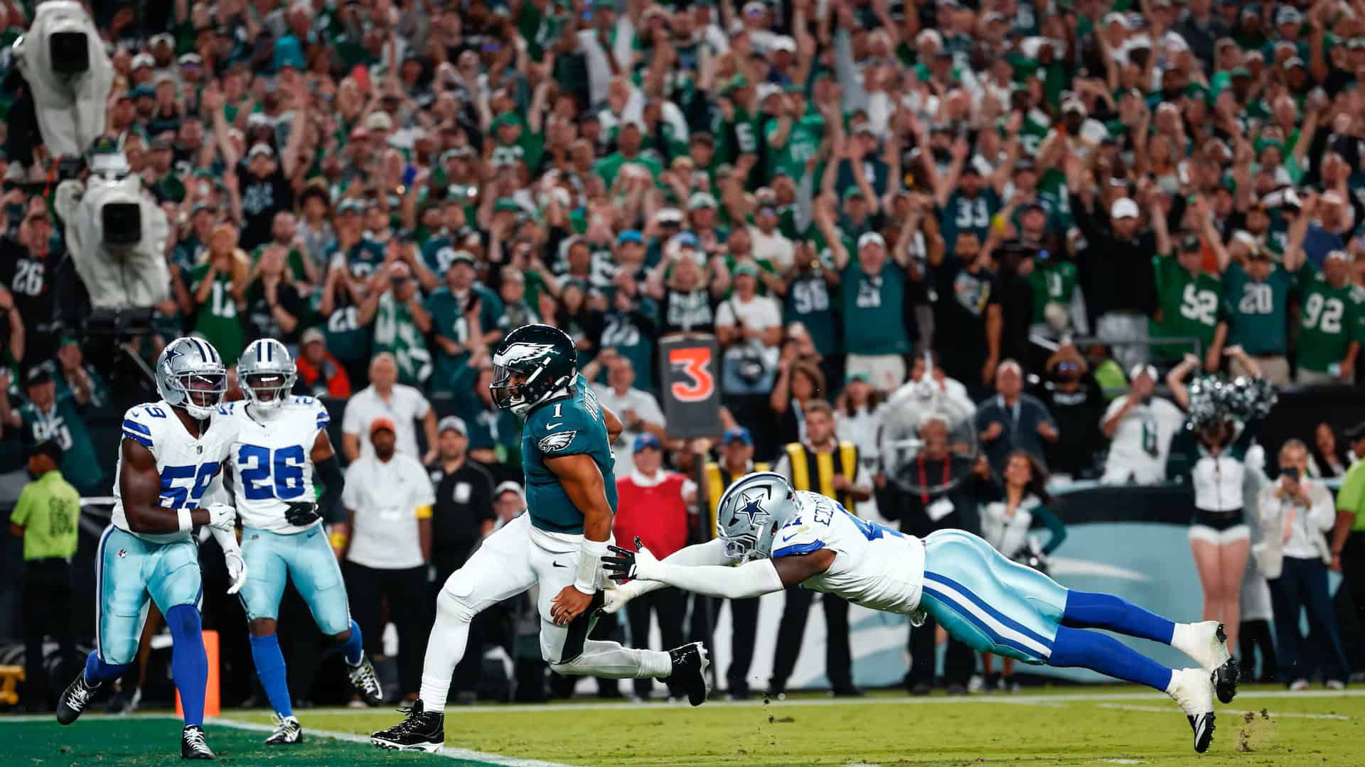 Spectacular football game action with a player from the Philadelphia Eagles evading a tackle from a Dallas Cowboys defender on the field during a high-stakes NFL game.
