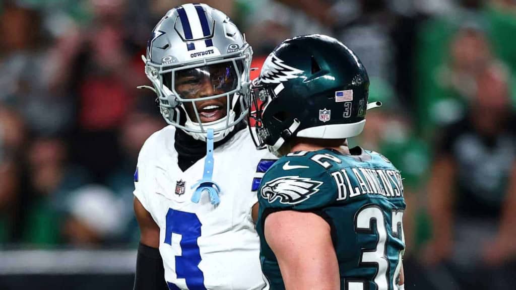 Dallas Cowboys player in white jersey talking to Philadelphia Eagles player in green jersey during an NFL game.