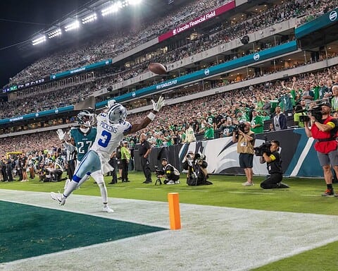 Seahawks player catching football in end zone during NFL game at Lincoln Financial Field with enthusiastic crowd and photographers capturing the moment.
