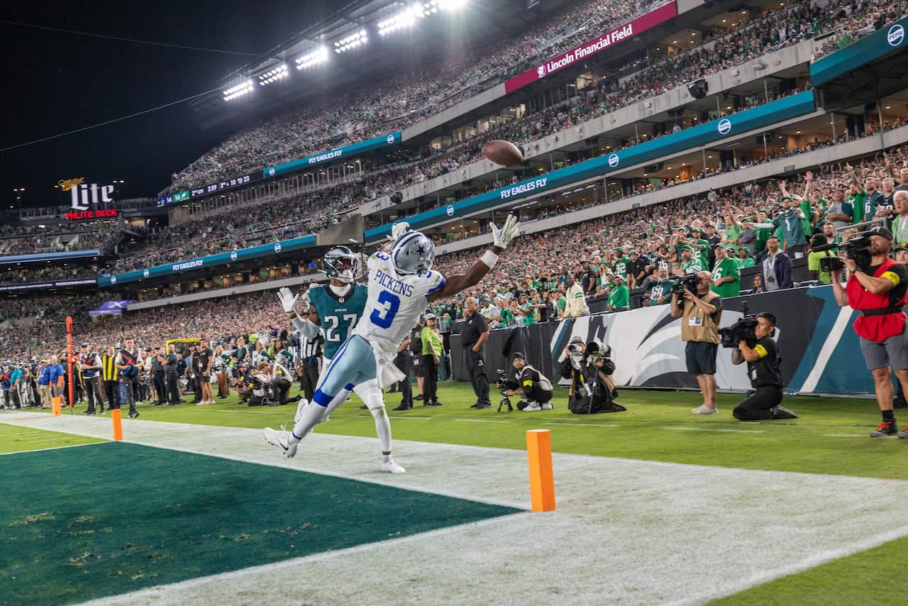Seahawks player catching football in end zone during NFL game at Lincoln Financial Field with enthusiastic crowd and photographers capturing the moment.