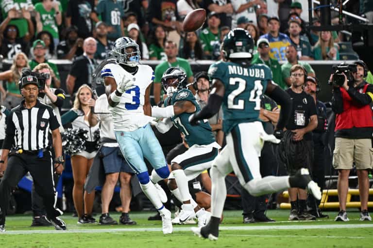 Dallas Cowboys wide receiver catching football during game against Philadelphia Eagles, with fans and cheerleaders in the background.