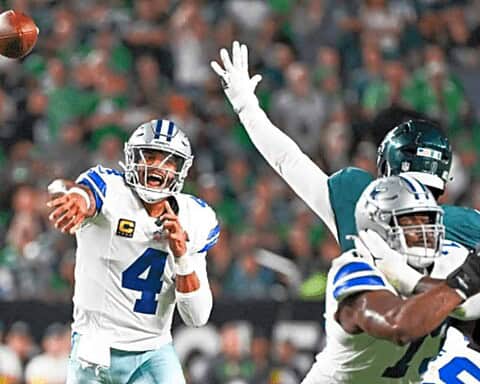 Quarterback Dak Prescott throwing a pass during an NFL game with Dallas Cowboys, with defensive players from the Philadelphia Eagles attempting to intercept, on a vibrant football field.