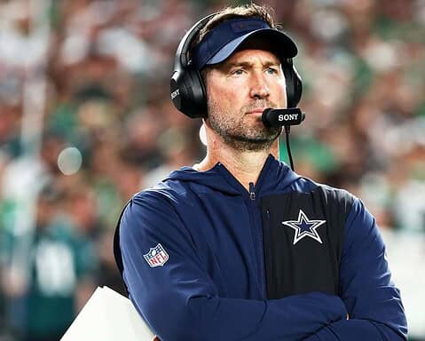 Head coach with headset at football game, Dallas Cowboys insider, wearing team jacket and cap, focused on game strategy, NFL football team, Inside The Star coverage, sports coaching.