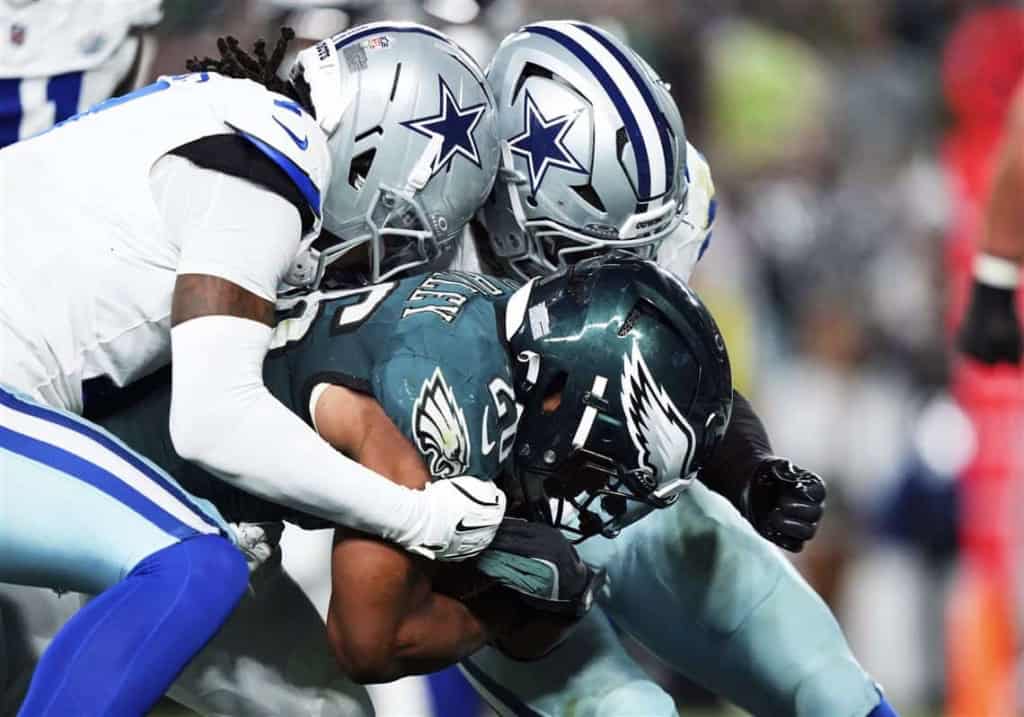 Aggressive tackle during an NFL game between Dallas Cowboys and Philadelphia Eagles, showcasing intense football action, player helmets, and team uniforms.