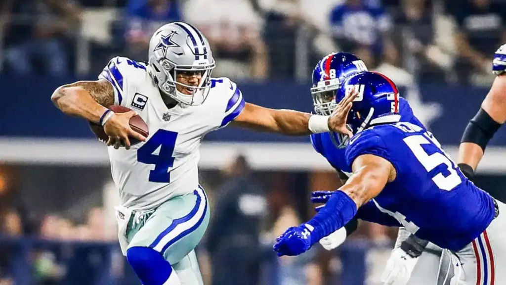 Dynamic NFC East football game featuring Dallas Cowboys quarterback Dak Prescott evading defensive players during an intense NFL match at AT&T Stadium.