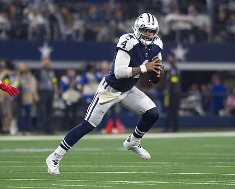 Dallas Cowboys football player running with the ball on the field during a game.
