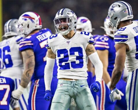 Dallas Cowboys football players celebrating during a game on the field during NFL season. Focus on player wearing jersey number 23 in a white and blue uniform.