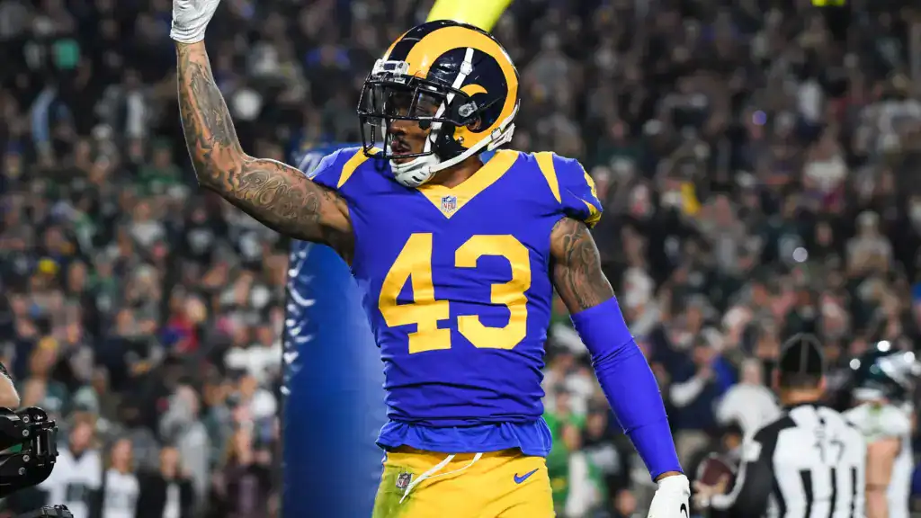 Rams football player wearing number 43 jersey celebrating on the field during a game, with a crowd and referee in the background, showcasing NFL action and team spirit.