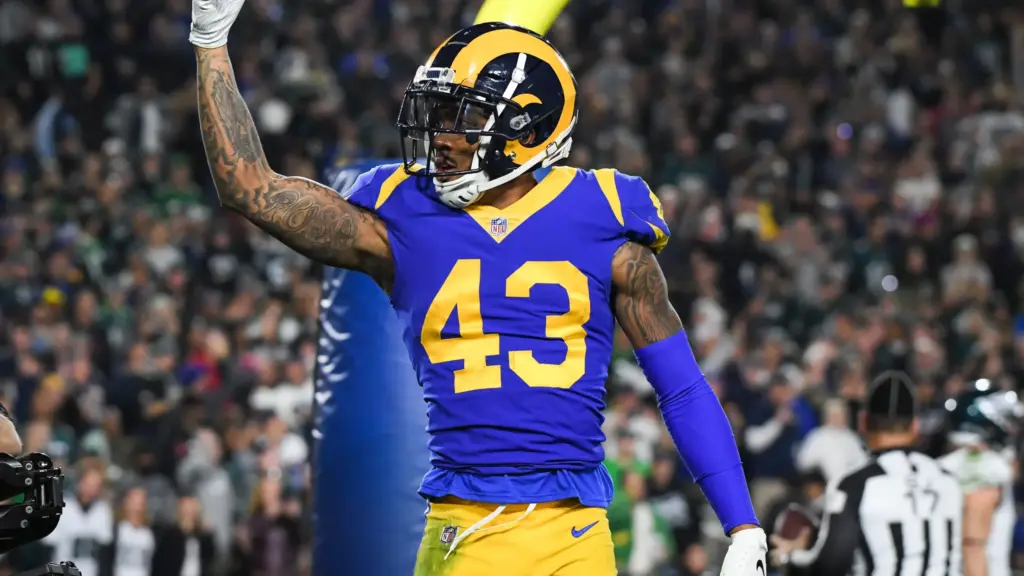 Rams football player wearing number 43 jersey celebrating on the field during a game, with a crowd and referee in the background, showcasing NFL action and team spirit.