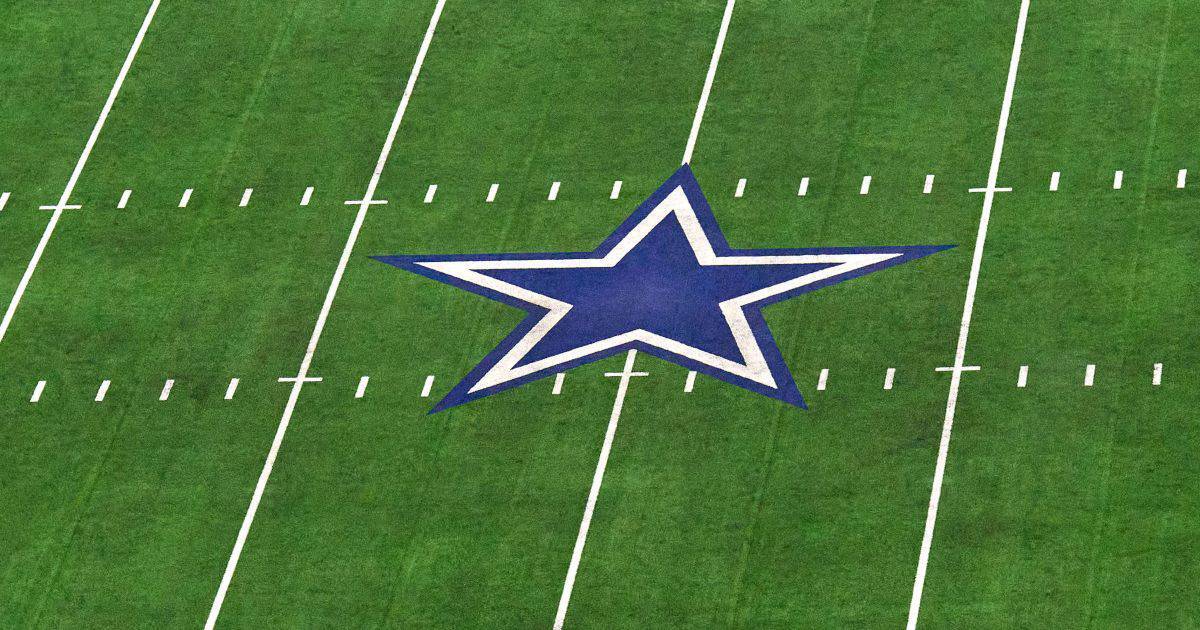 Dallas Cowboys star logo on the football field, representing the NFL team, inside AT&T Stadium, with bright green turf and white yard lines.
