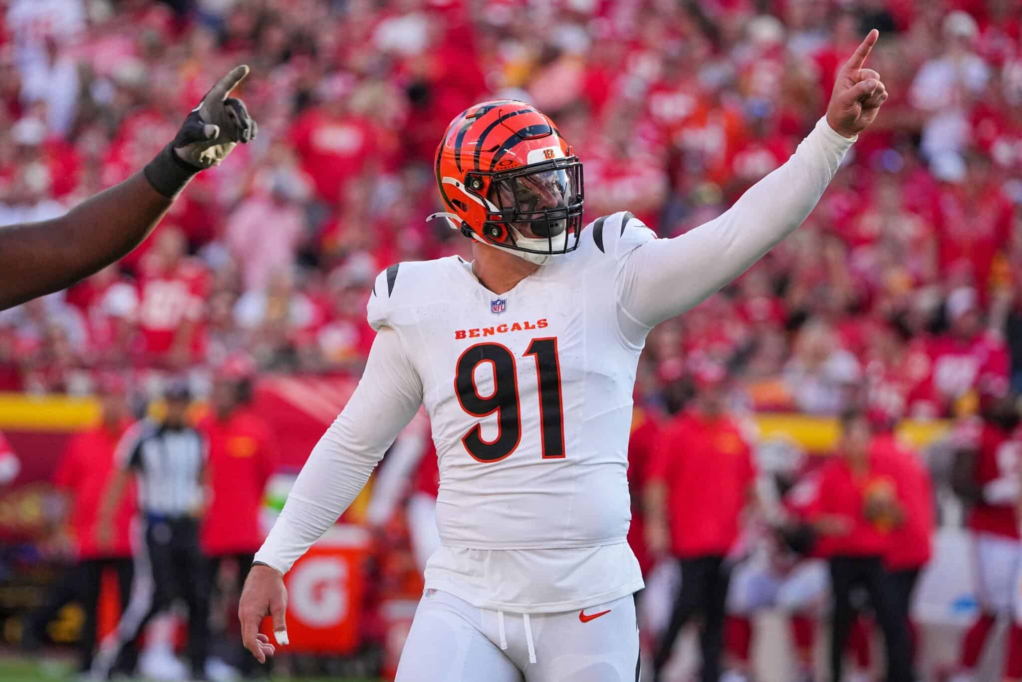 Cincinnati Bengals player celebrating on the football field during a game, wearing a white uniform with the number 91, with a crowd in the background.