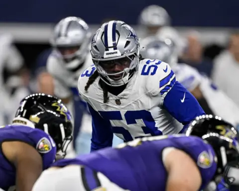 Dallas Cowboys football player in action during a game, wearing team uniform, helmet, and protective gear on the field.