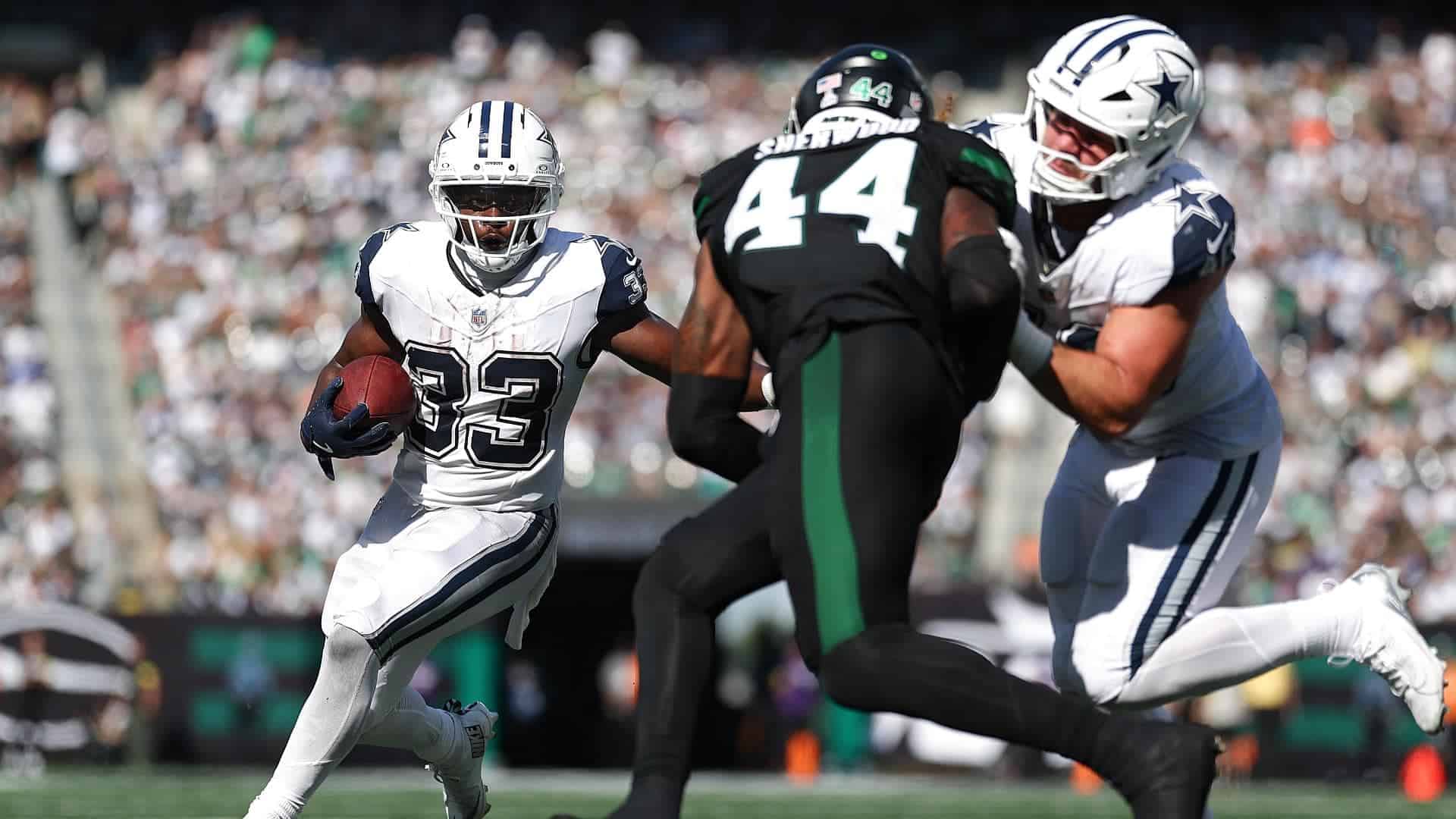Running back with the football evades two defenders during an National Football League game, showcasing the Dallas Cowboys' offensive play against the opposing team.